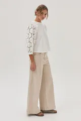 Blusa blanca de mangas 3/4 con bordado calado y cuello redondo con volados.