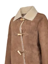Chaqueta de gamulán de cuero color caramelo, con interior forrado en shearling. Presenta cuello clásico de borrego, cierre frontal con botones tipo toggle de madera y detalles de costura.