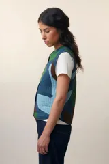 Chaleco acolchado con estampado abstracto en tonos azules y verdes, con cuello en V y cierre frontal con botones.