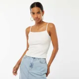 Camiseta sin mangas blanca de canalé con tirantes finos y detalle de encaje en el escote.