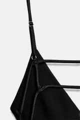 Vestido midi negro de tejido satinado, con escote en pico y tirantes finos ajustables. Presenta un detalle de tiras cruzadas en la espalda descubierta y cierre con cremallera metálica.