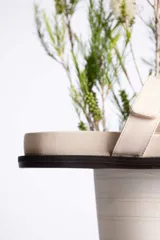 Sandalia plana color beige con dos tiras anchas en el empeine y suela negra.