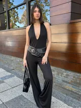 Mono largo negro con escote halter y espalda descubierta. Incluye cinturón ancho de cuero sintético con tachas plateadas.