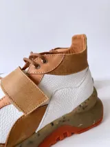 Zapatillas deportivas blancas con detalles en cuero color salmón y suela gruesa con detalles en naranja.
