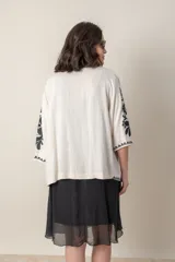 Saco color crudo de lino y viscosa con bordado de hilo de seda negro, de corte suelto y mangas tres cuartos.