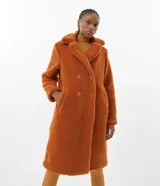 Campera larga de sherpa color marrón, con cuello solapa, cierre con botones y bolsillos laterales. Forro de poliéster.