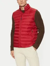 Chaleco rojo Tommy Hilfiger plegable, con cuello chimenea, cierre de cremallera, dos bolsillos laterales con cremallera y logo bordado en el pecho. Confeccionado en tejido de nailon que repele el agua.