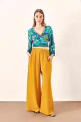 Pantalón palazzo color mostaza, de tiro alto y corte holgado.