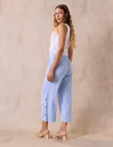 Pantalón blanco de algodón con pretina elastizada, bolsillos inclinados y ruedo lateral con tajo y botones.