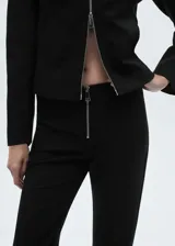 Chaqueta negra de corte recto con cuello camisero y cierre de cremallera doble.