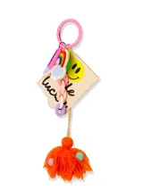 Llavero con aro rosado y dijes colgantes: arcoíris, nube, lápiz labial, smiley face, cadena de eslabones y borla de hilo naranja con lunares de colores.