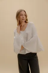 Blusa blanca de algodón bordado con escote en V y mangas amplias acampanadas con detalle de calado.