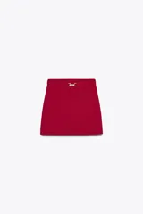 Falda mini roja de punto liso con cintura elástica y cinturón con hebilla dorada.