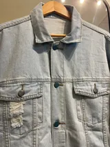 Campera de jean celeste con cuello clásico, cierre con botones metálicos y bolsillos con solapa en el pecho.