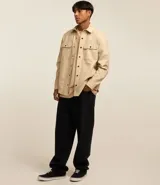 Camisa marrón de manga larga, confeccionada en sarga, con cuello inglés, abotonado delantero, bolsillos en el pecho con solapa y puños abotonados.
