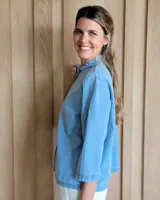 Camisa negra con mangas fruncidas, botones de nácar y pespuntes contrastantes.
