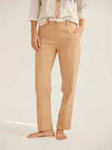 Pantalón cigarette color beige, de corte recto y tiro medio, con bolsillos laterales y cierre frontal con botón y cremallera.