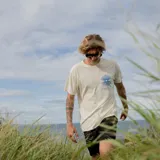 Remera blanca de manga corta con estampado en el pecho de un diseño abstracto en color celeste y texto.