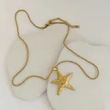 Collar dorado con cadena de eslabones retorcidos y dije de estrella de mar con diseño de espiral en el centro.