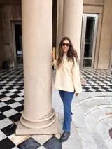 Canguro de paño color crema, de corte holgado y cuello redondo, con puños y ruedo acanalados.