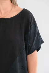 Blusa negra de lino con cuello redondo, mangas cortas y detalle de bordado calado en los laterales y el ruedo.