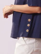 Blusa azul de algodón marca Erika, de manga corta amplia y cuello redondo. Presenta aberturas laterales con botones.