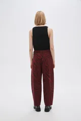 Pantalón de jean de tiro alto con estampado animal print de cebra en tonos borgoña y negro.