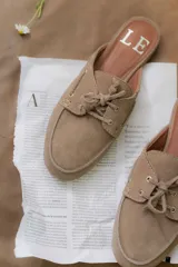 Mocasines tipo mule color beige, con detalle de cordones y ojales metálicos.