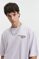 Remera color café de corte oversize con cuello redondo y mangas cortas. Estampado en la espalda con la frase "Stay Original Forever" y varios diseños gráficos.