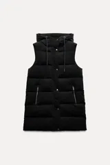 Chaleco largo acolchado negro con capucha ajustable con cordones y manga sisa. Bolsillos laterales con cremallera. Cierre frontal con cremallera y solapa con botones a presión.