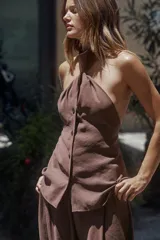 Chaleco top marrón con cuello halter, detalle de nudo y cierre frontal con botones.