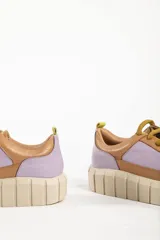 Zapatillas deportivas de cuero color beige con detalles en lila y amarillo.