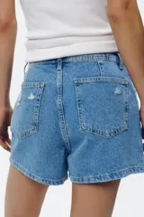 Falda pantalón de jean de tiro alto con cinco bolsillos, efecto lavado y roturas frontales. Cierre frontal con cremallera oculta y botones.