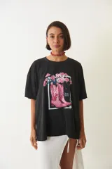 Remera negra de corte amplio con estampa de botas de cowboy rosas y flores.