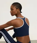 Top deportivo sin copa, color bordó, con escote en U y espalda tipo nadador. Presenta ribetes de color blanco en el contorno del escote y las sisas.