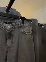 Pantalón de jean gris con efecto lavado y detalles de tachas en el bolsillo.