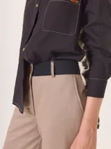 Pantalón de vestir color marrón, corte cigarette (pierna angosta) con tajo en el bajo. Presenta una cintura elástica ancha de color beige claro.