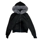Campera corta negra con capucha y cierre frontal, confeccionada en poliéster. Tiene corte boxy y piel sintética gris alrededor de la capucha.