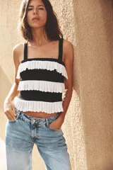 Top tejido de punto negro con tirantes anchos y volantes blancos en contraste.