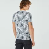 Remera blanca con estampado de hojas de palmera en tonos verde y azul.