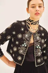 Saco corto negro, ajustado al cuerpo, con escote redondo y bordado a mano en frente, espalda y mangas con lentejuelas y pedrería en forma de estrellas y motivos florales.