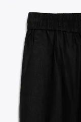 Pantalón negro de lino, de tiro alto con cintura elástica ajustable con cordones, bolsillos delanteros y pernera recta.