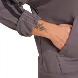 Hoodie Adidas color lila con capucha y cordones ajustables, bolsillo tipo canguro y logo bordado en el pecho. Presenta las tres tiras características de la marca en color negro a lo largo de las mangas.