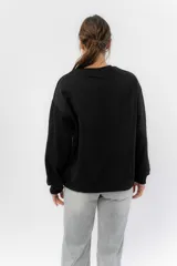 Buzo negro de algodón rústico con estampa frontal multicolor de labios. Corte relajado, cuello redondo y terminaciones en rib.