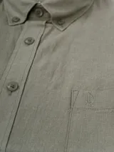 Camisa de hombre color verde oliva, de manga corta y corte clásico. Confeccionada en lino y poliéster, con cuello abotonado y bolsillo en el pecho.