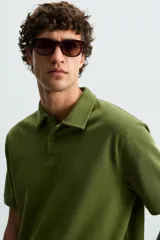Polo de piqué color crudo, corte regular fit, cuello solapa con cierre de botonadura y mangas cortas.
