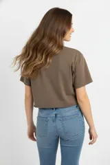 Remera cropped color borgoña de algodón, con cuello redondo y mangas cortas. Estampado frontal con un corazón sagrado con llamas, rosas y la leyenda 'Love Blooms'.