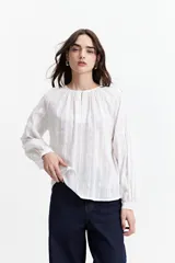 Blusa blanca de manga larga con detalle de tablas en el frente y puños.