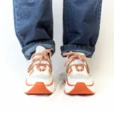 Championes urbanos blancos con detalles en naranja y cordones con patrón de rombos en blanco y naranja.