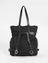 Mochila tipo shopper de poliéster color negro, con asas de cuero sintético negro y cordones ajustables laterales con terminaciones en rojo y blanco. Presenta un bolsillo frontal con cierre metálico plateado y un pequeño logo bordado en la parte inferior.